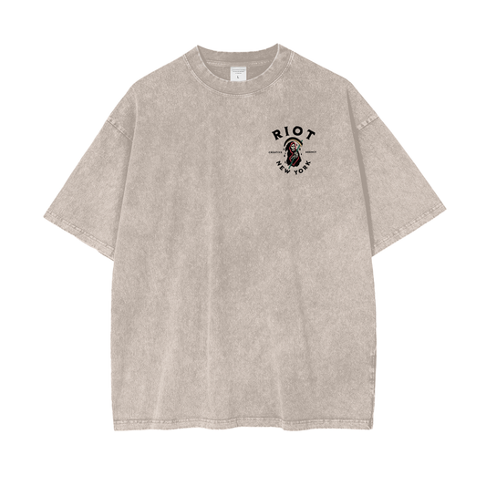 Front of apricot snow-washed oversized t-shirt with small RIOT reaper crest on chest