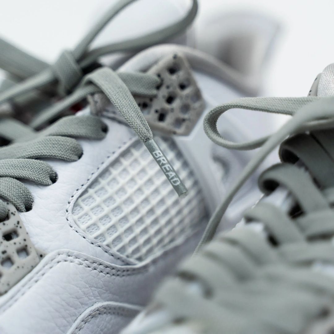 Macro shot of Bread Vulture Gray shoelace aglet with logo on white sneaker