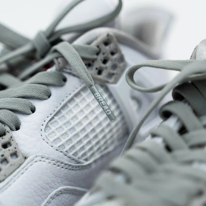Macro shot of Bread Vulture Gray shoelace aglet with logo on white sneaker