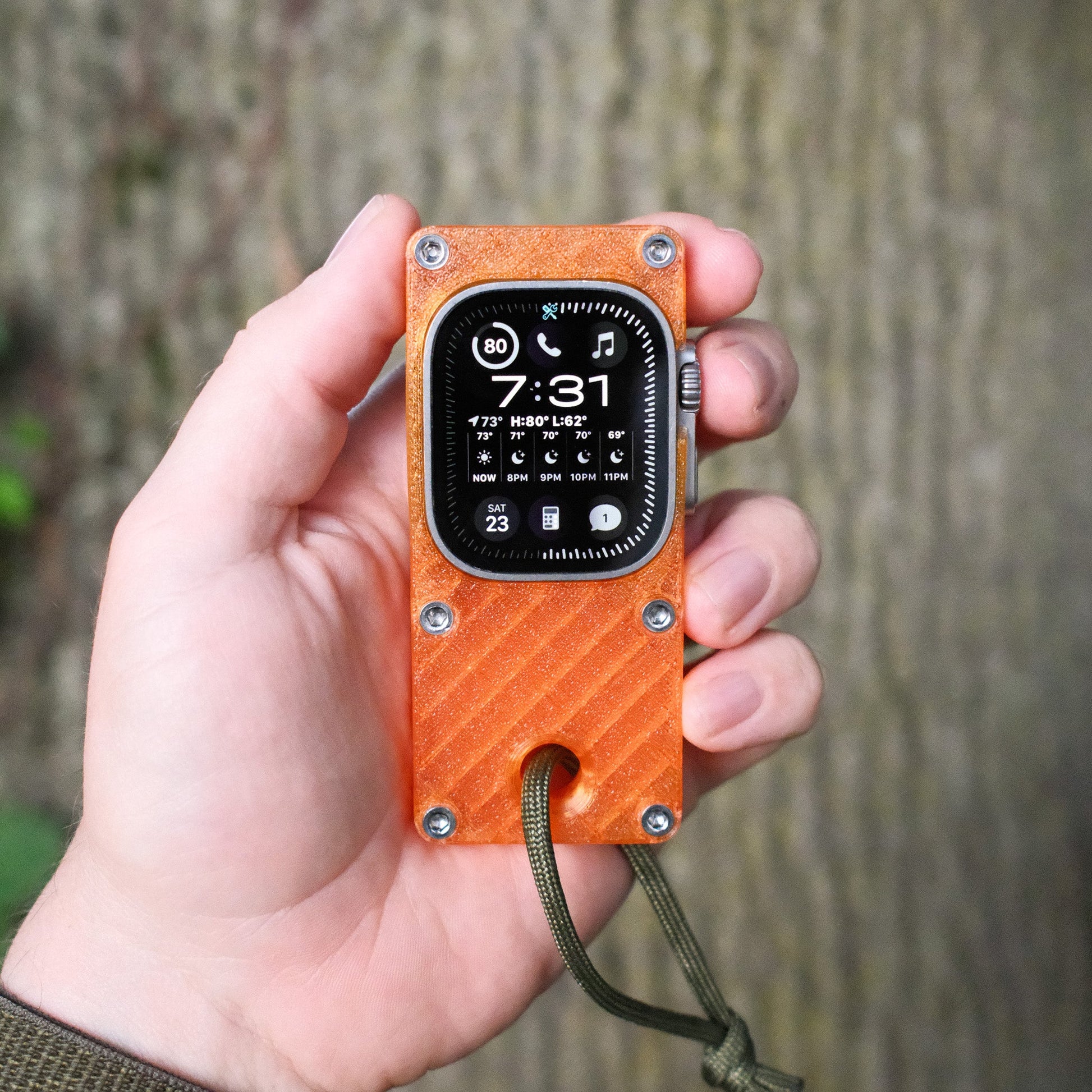 hand holding orange miniphone ultra Apple Watch Ultra case outdoors
