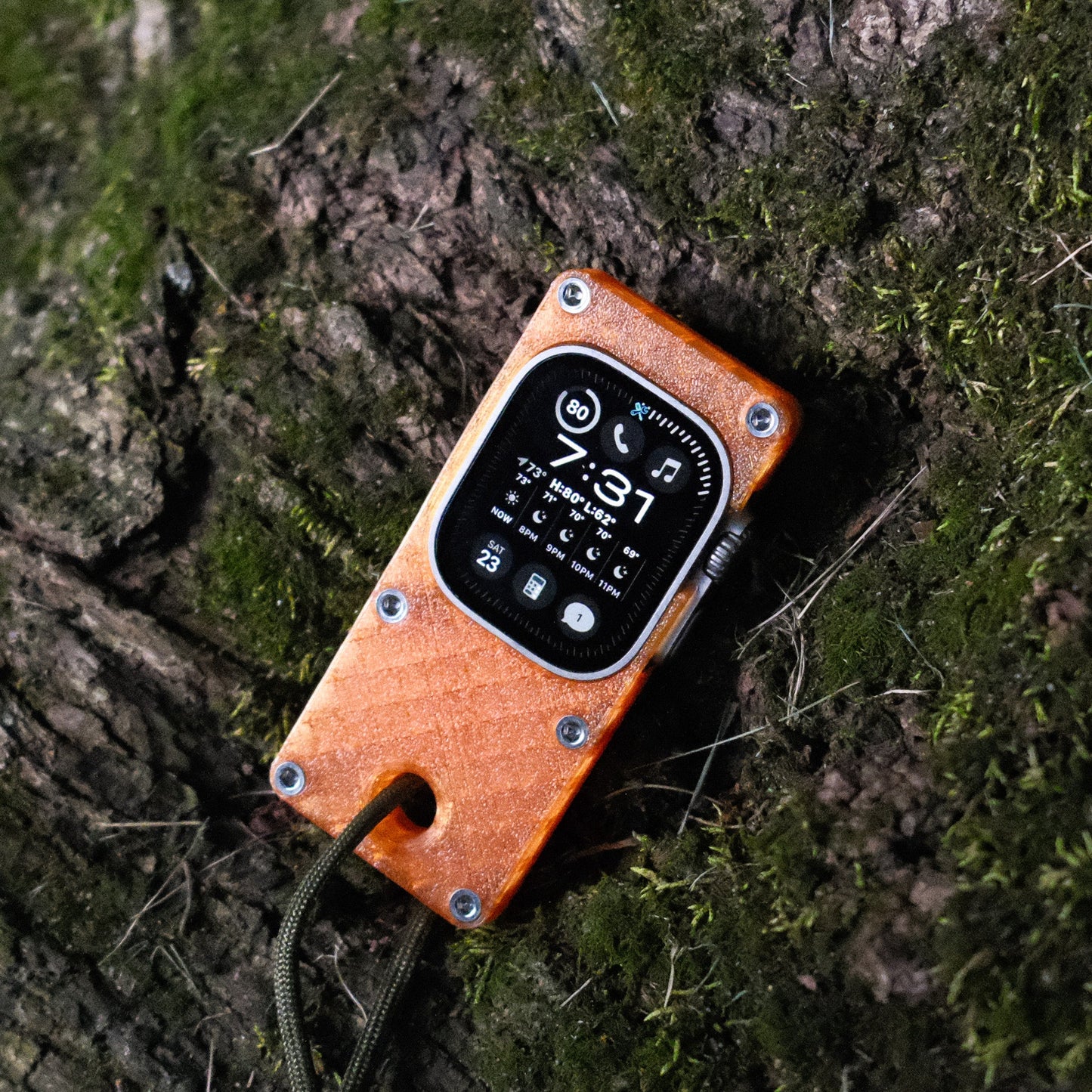 miniphone ultra orange Apple Watch Ultra case resting against tree bark outdoors