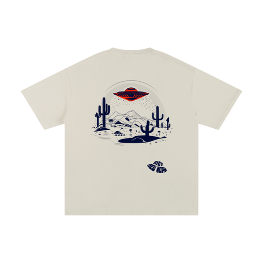 Sandstone beige tee back with UFO flying saucer over desert scene, cactus silhouettes, mountains, and RIOT NEW YORK warped mark.