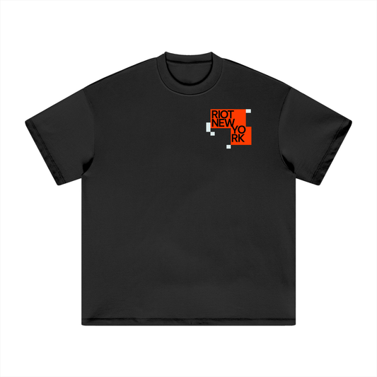 Black tee front with stacked orange ‘RIOT NEW YORK’ tiles and small glitch squares.