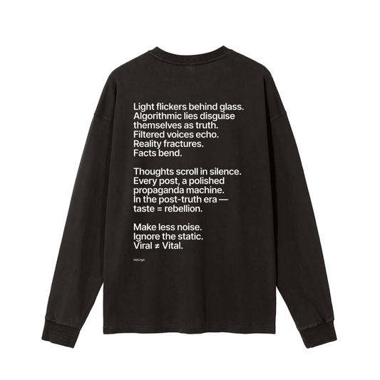 Washed black long‑sleeve back with white manifesto text block ending ‘Vital ≠ Viral’ and small ‘riot.nyc’ mark.